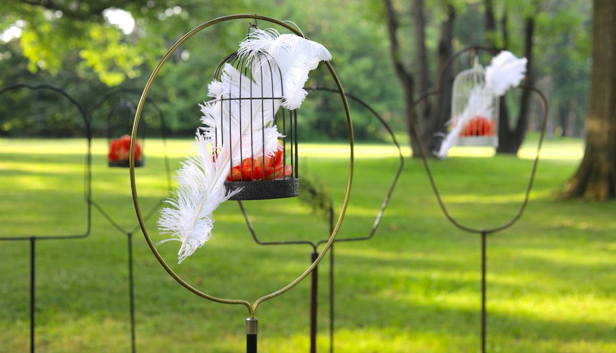 Outdoor garden birdcage stands decorated with white feathers and florals