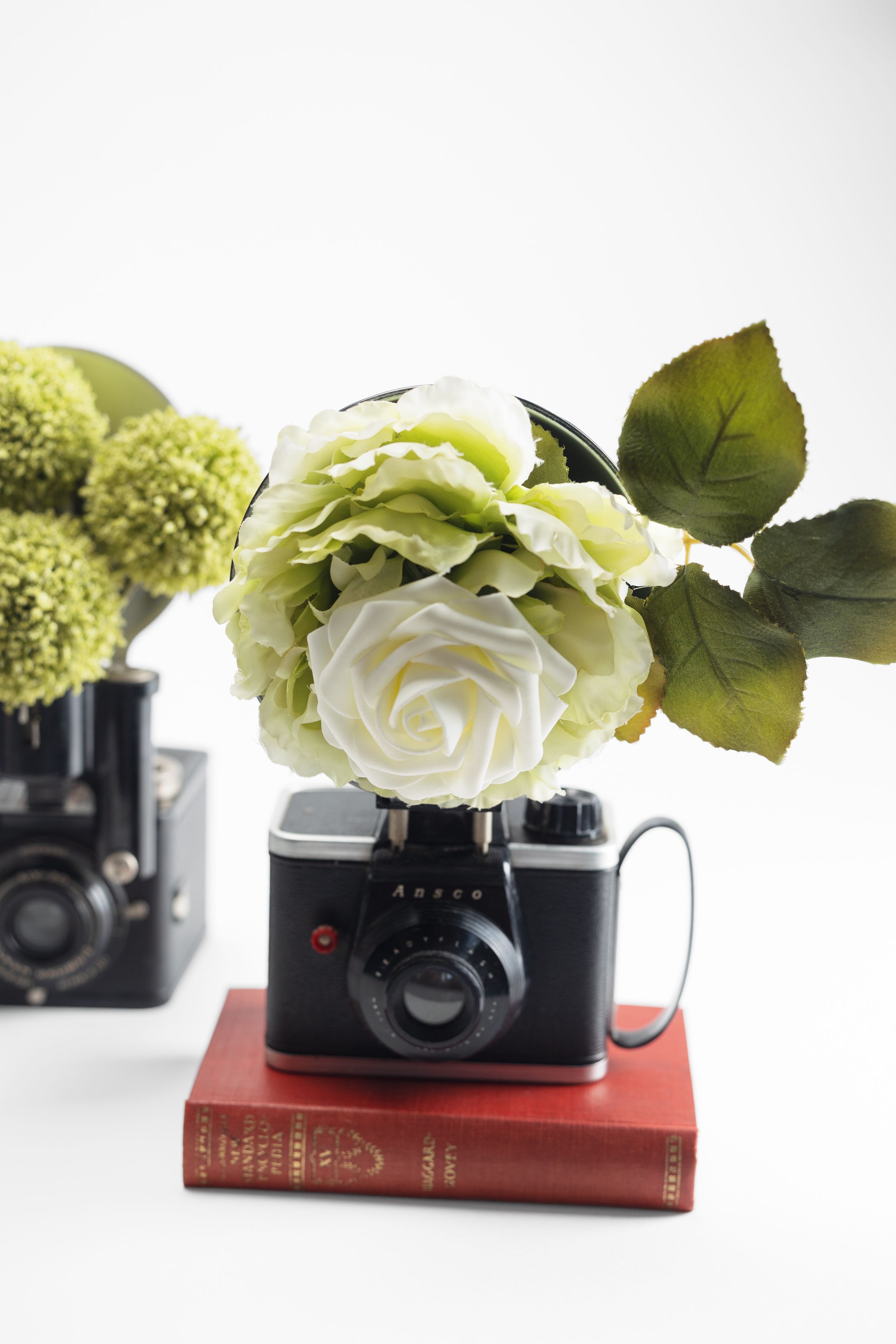 Vintage Ansco camera styled with floral topper and red antique book