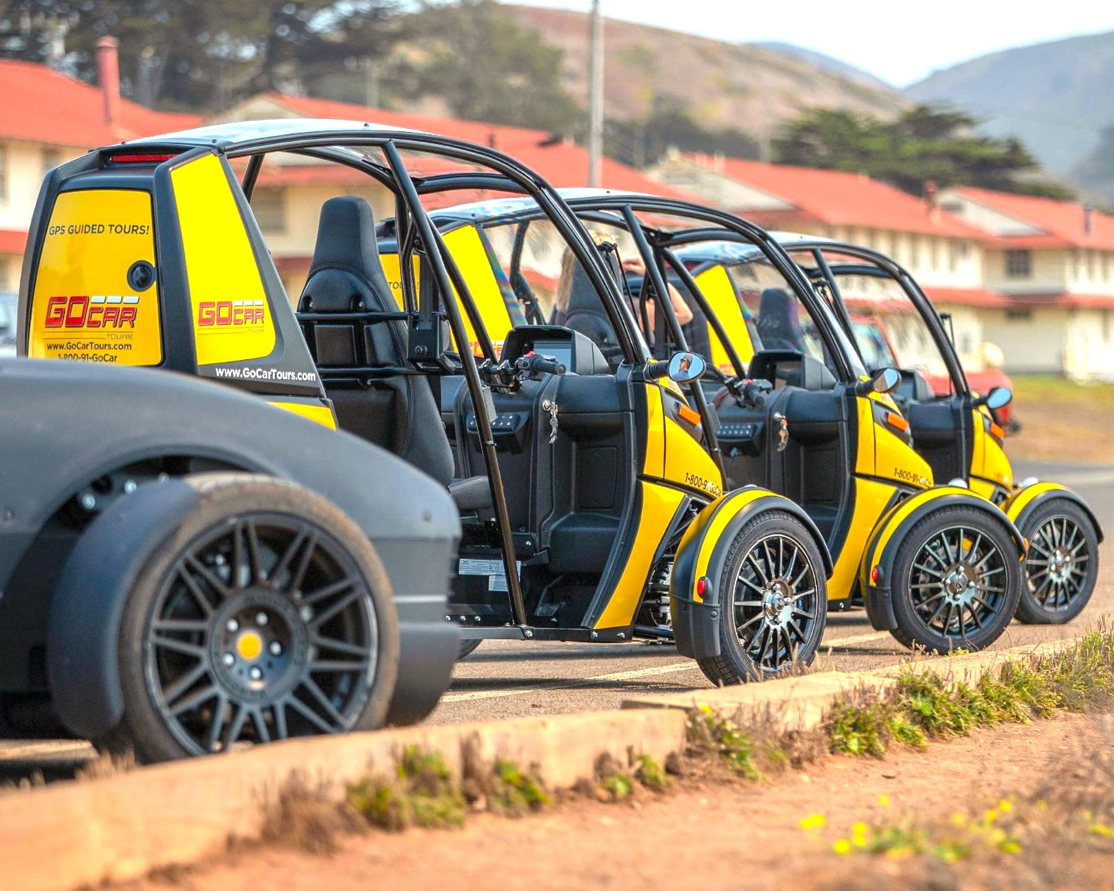 Line of yellow electric cars parked in a row, ready for a guided tour, in a sunlit outdoor area