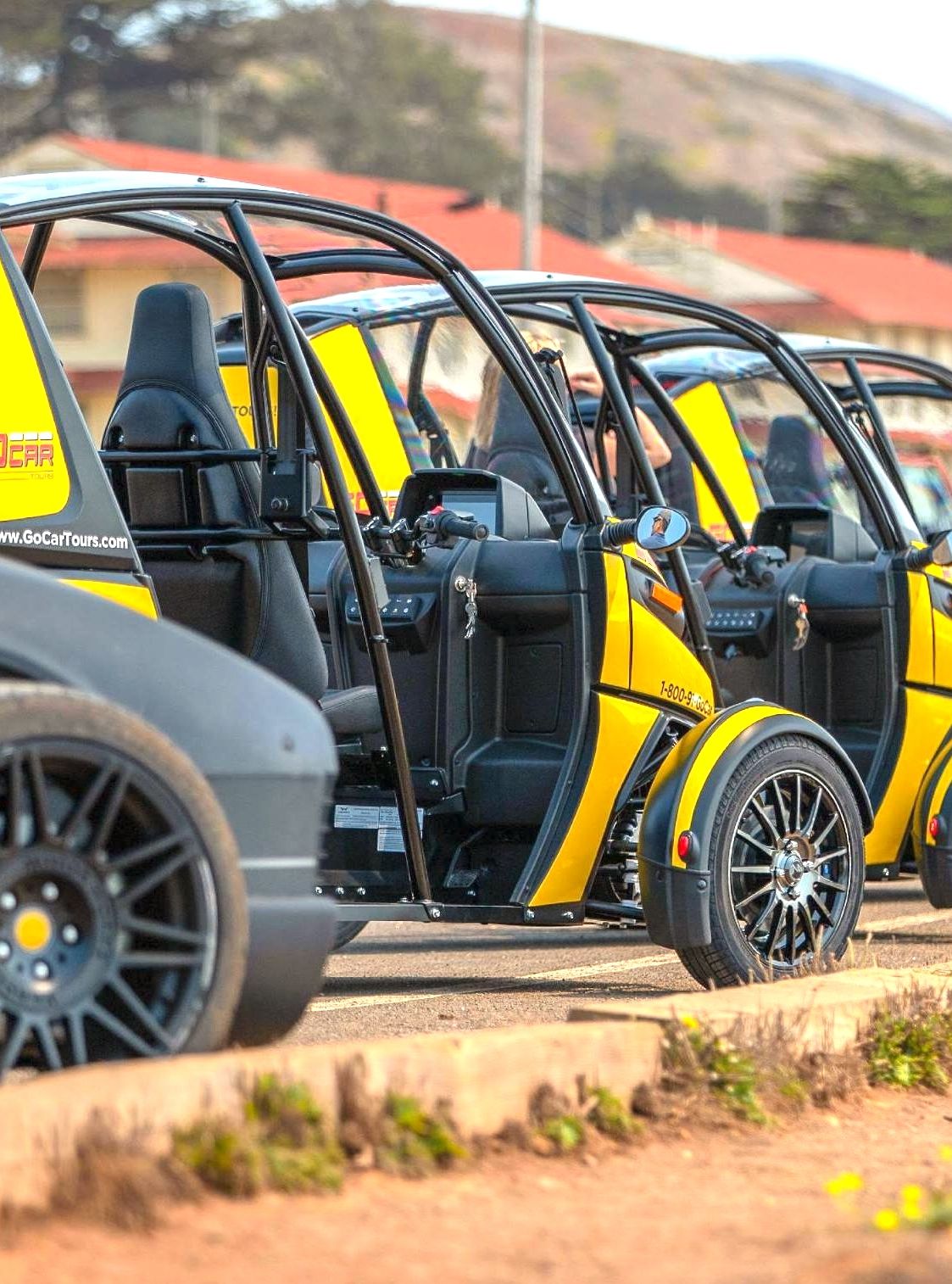 Line of yellow electric cars parked in a row, ready for a guided tour, in a sunlit outdoor area