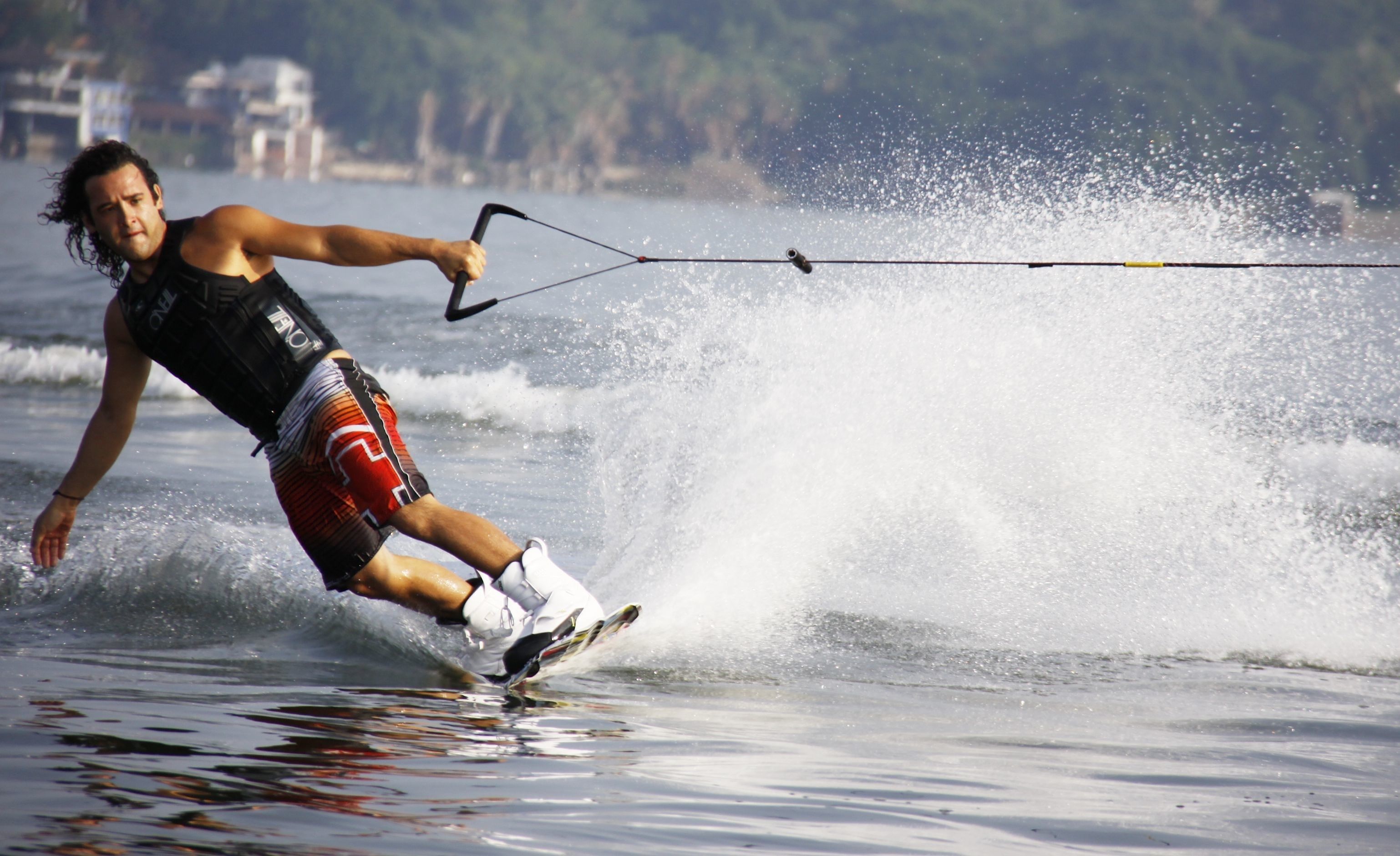 Wakeboarder gliding across the water's surface, performing a turn while being pulled by a cable