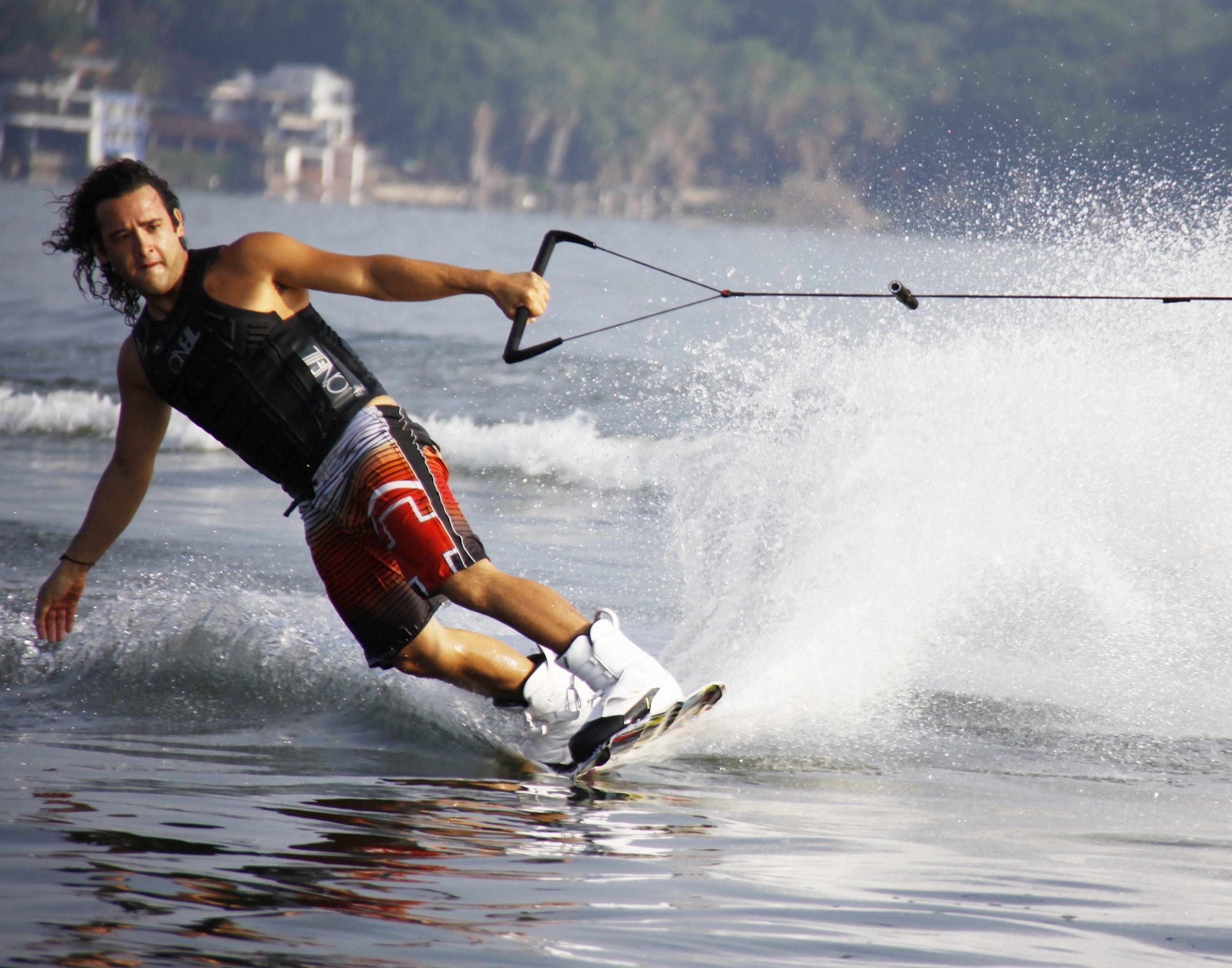 Wakeboarder gliding across the water's surface, performing a turn while being pulled by a cable