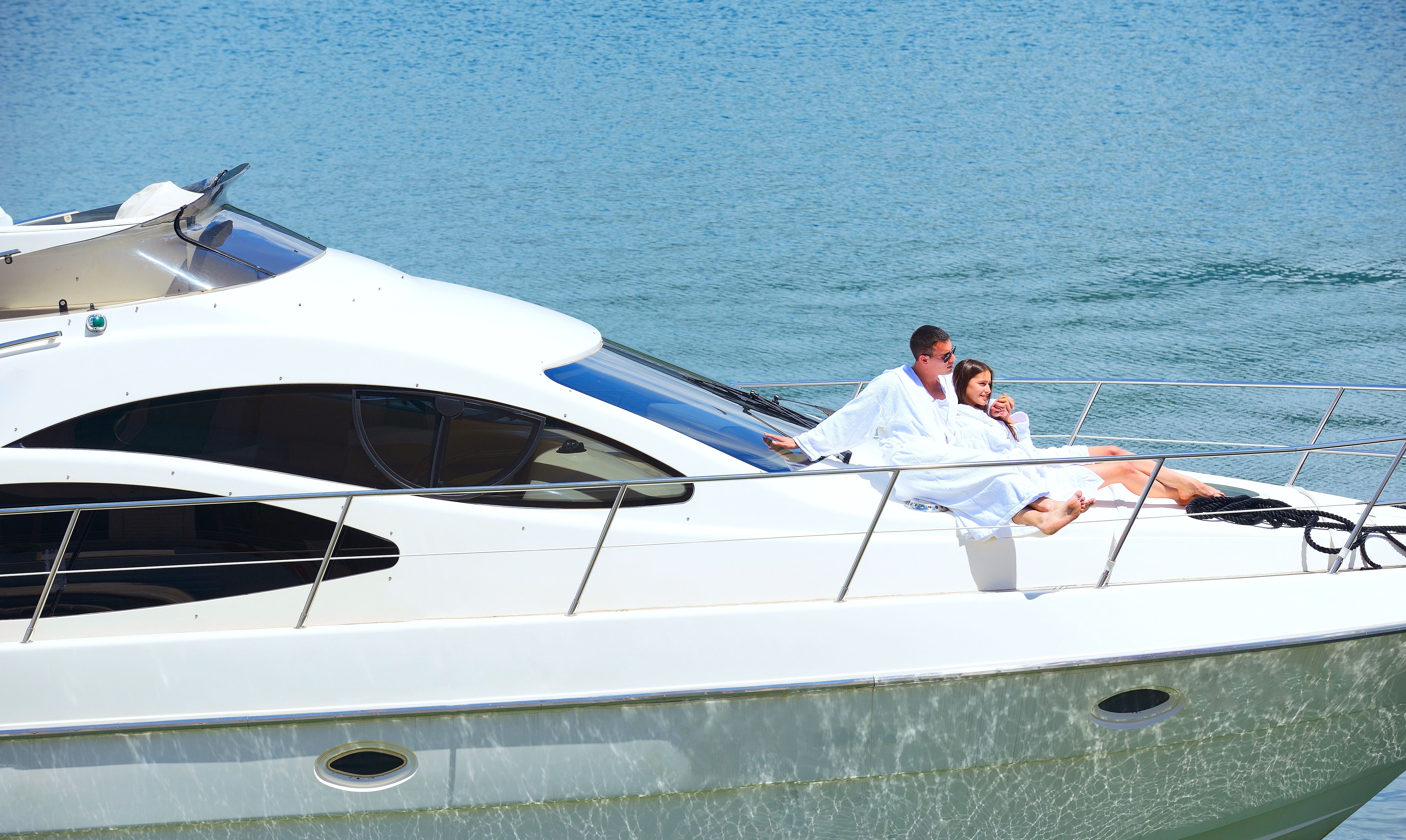 Couple relaxing in white robes on the deck of a luxury yacht, enjoying a peaceful moment on the water