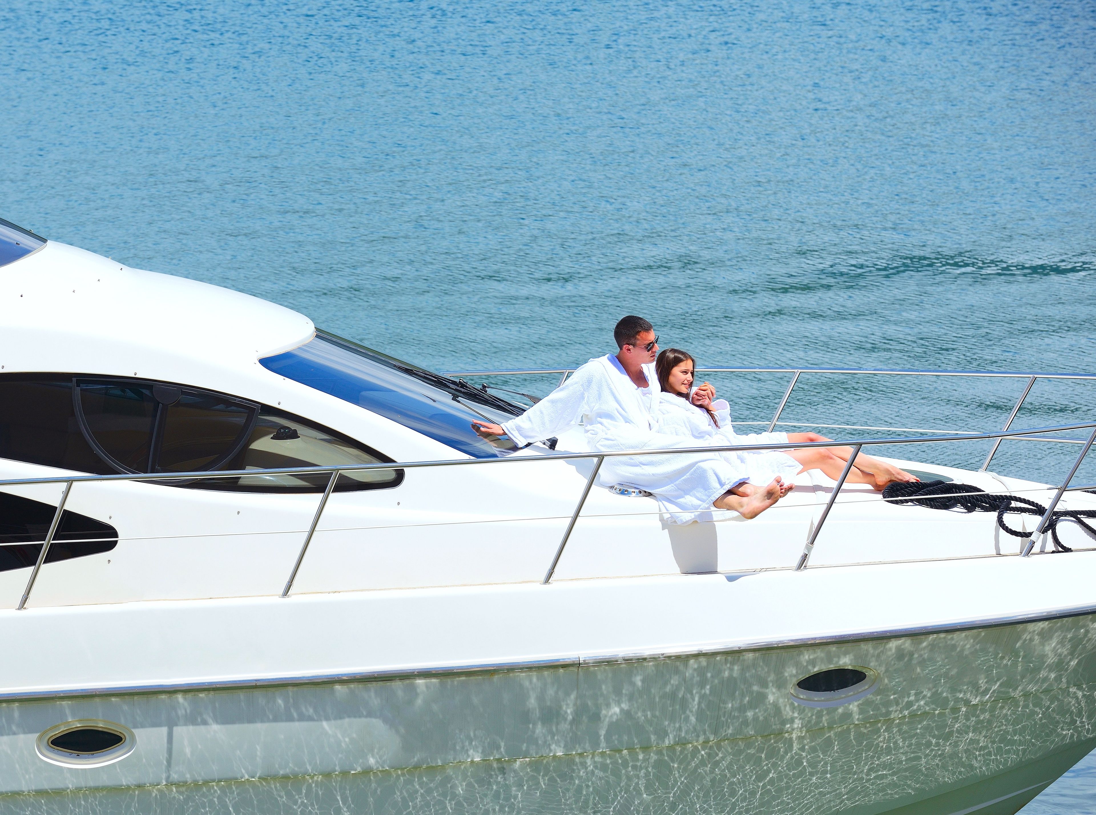 Couple relaxing in white robes on the deck of a luxury yacht, enjoying a peaceful moment on the water