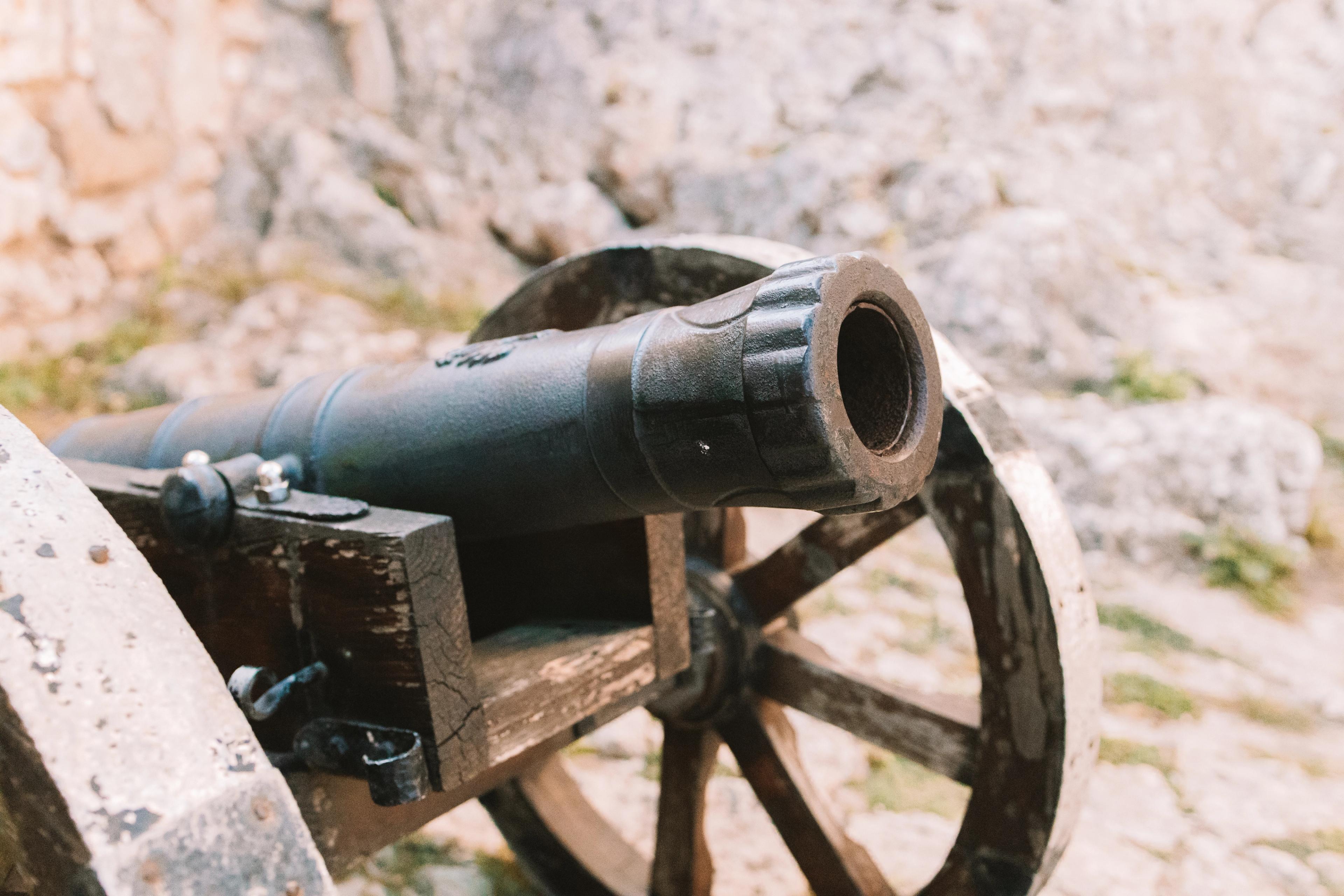 Close-up of an old cannon on a stone surface, reflecting a historical setting