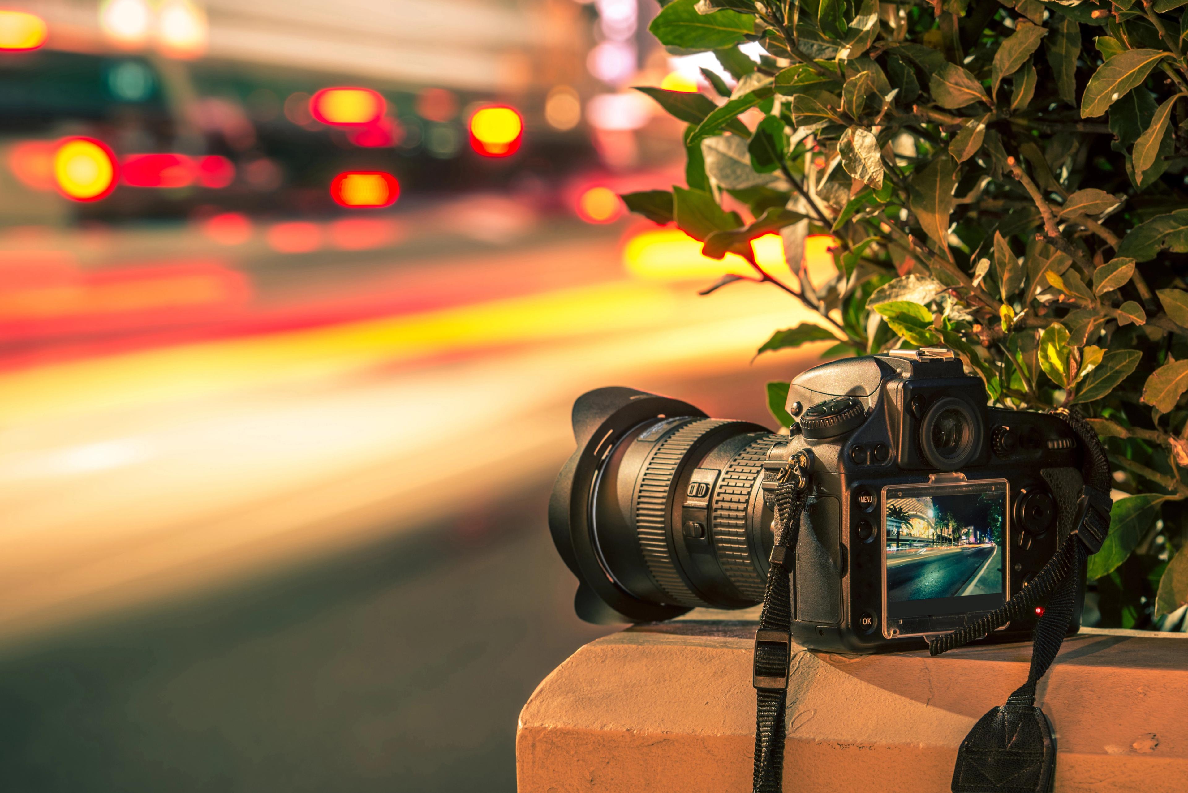 A camera positioned on a ledge, set up to capture a long exposure of city traffic lights at night