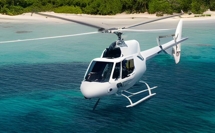 Helicóptero blanco volando sobre aguas turquesas cristalinas cerca de una playa aislada con árboles verdes