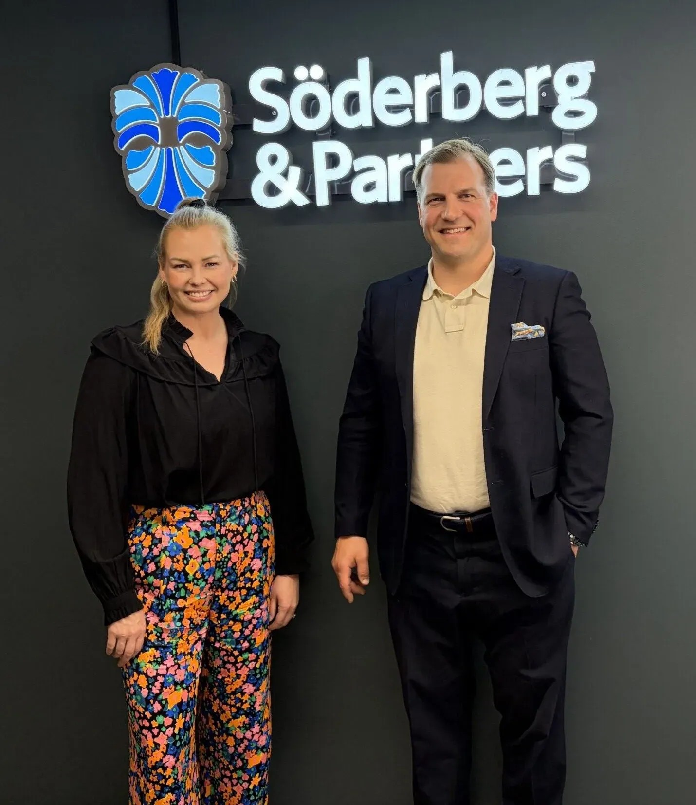 Söderberg & Partners' økonomidirektør Anu Suomilammi og Finadeck Oys administrerende direktør Saku Pöllänen foran Söderberg & Partners' logo