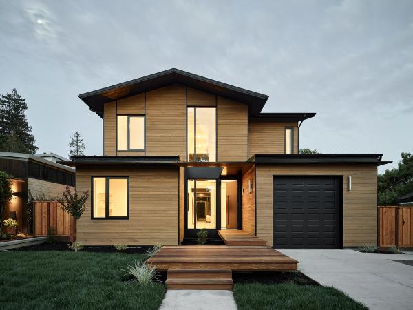 Modern wood-clad two-story home lit at dusk