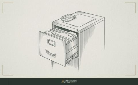 Antique engraving illustration. A filing cabinet drawer pulled open, folders standing upright and labeled, one sheet pressed flat under a glass paperweight on top.