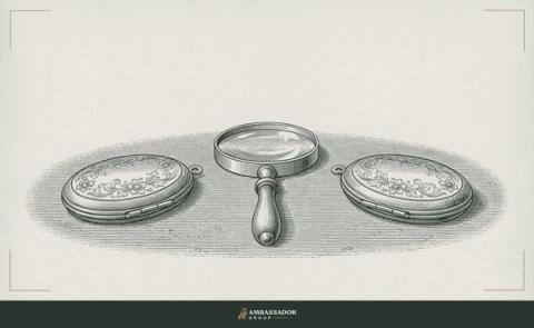 Antique engraving illustration. Two closed lockets on a table, each facing away from the other, a magnifying glass centered between them, lens pointed upward.