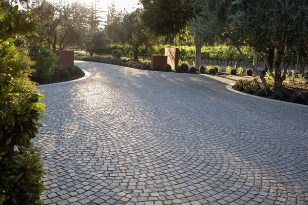 Cobblestone fan-pattern driveway lined with plantings
