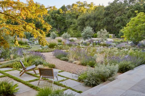 Gravel garden terrace with lounge chairs among drought-tolerant plantings