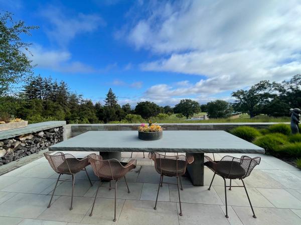 Stone dining terrace with an outdoor table overlooking a wooded valley