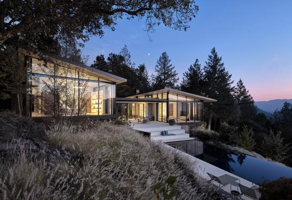 Hillside glass home at dusk above an infinity pool