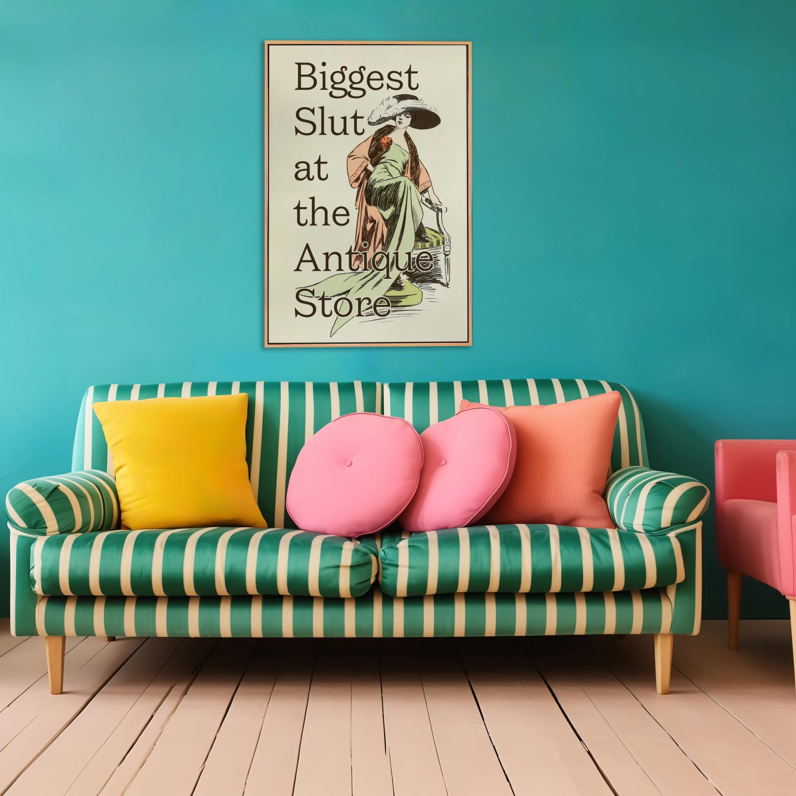 Framed vintage-style print reading "Biggest Slut at the Antique Store" hung above a green striped sofa with colorful pillows.