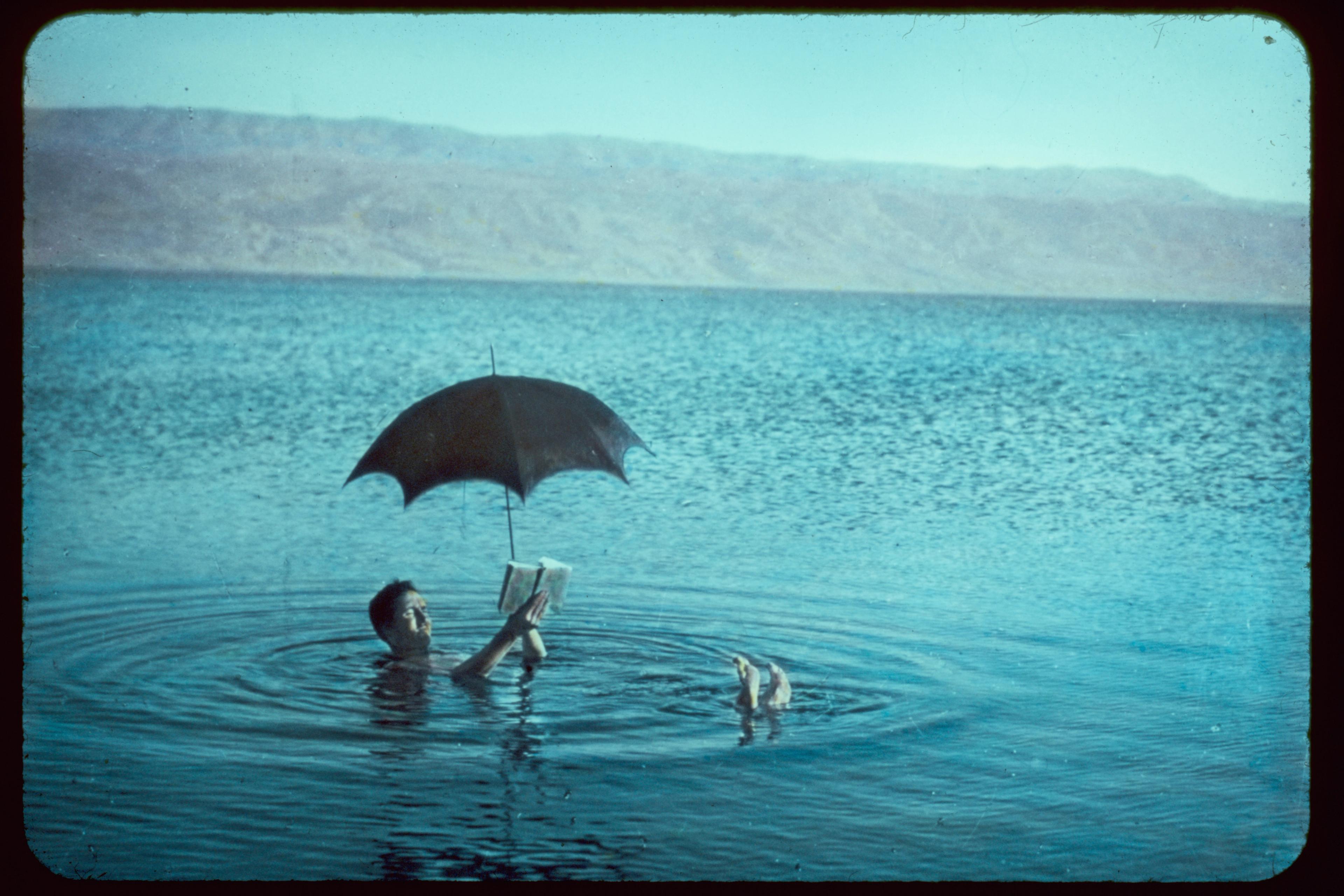 Man With Book and Sunshade Floating to Show Buoyancy