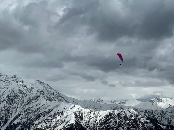 Pink paraglider above moody snow-clad peaks