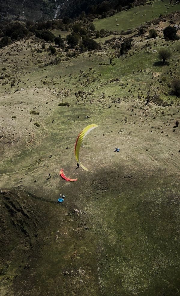 Top-down aerial of pilot landing on a green Bir slope