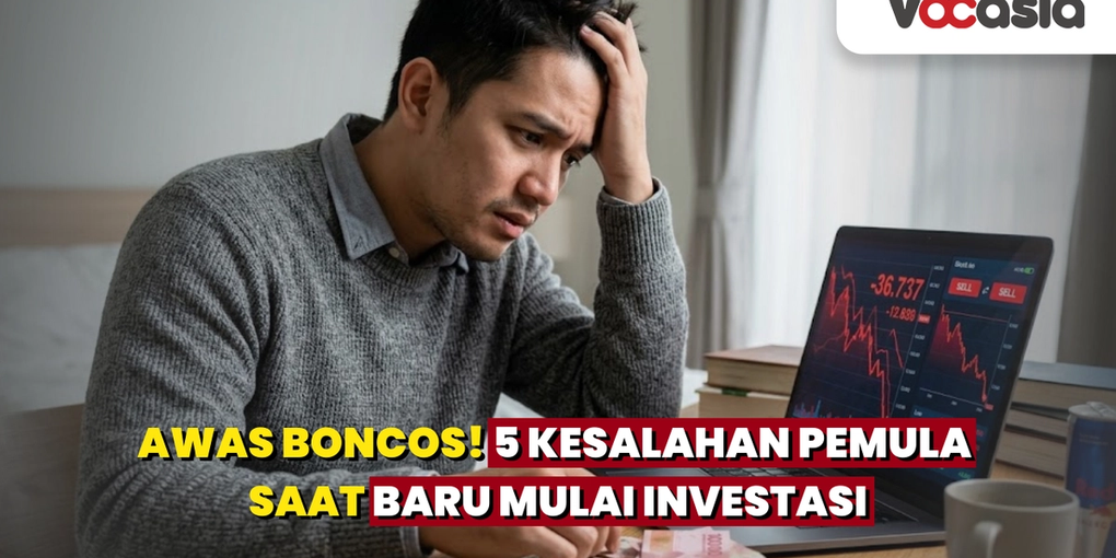 Pria stres memegang kepala saat melihat grafik saham merah menurun di laptop dengan uang Rupiah berserakan di meja akibat kerugian investasi.