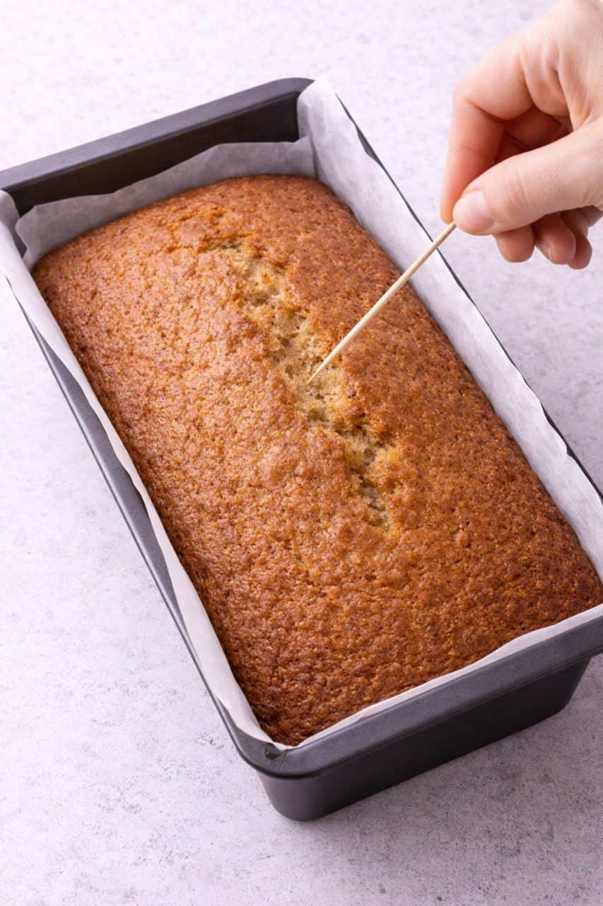 Testing peanut butter banana bread with a toothpick for doneness