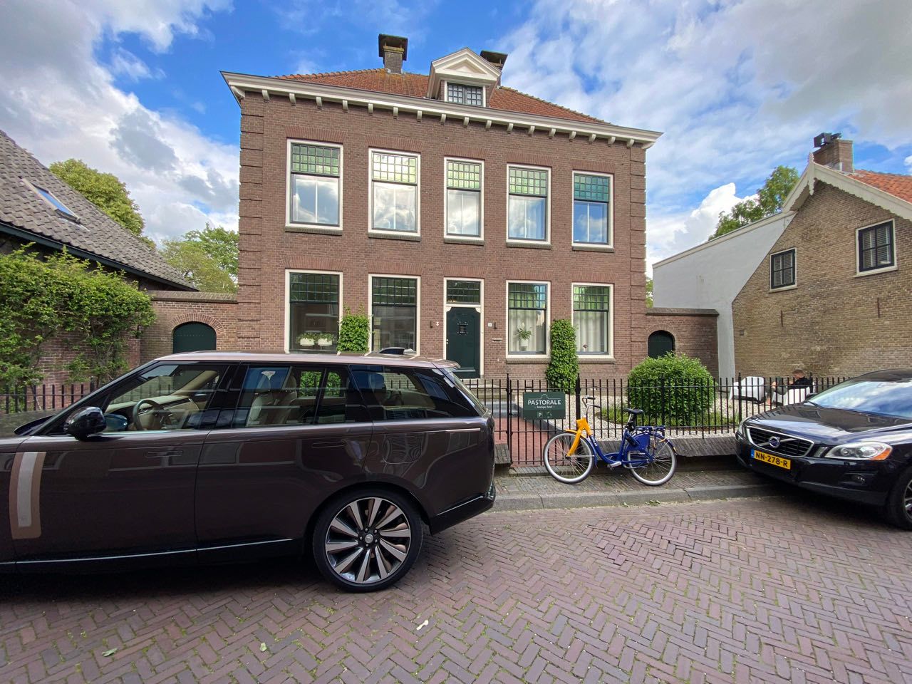 Boutique hotel with two expensive cars and an OV-fiets.