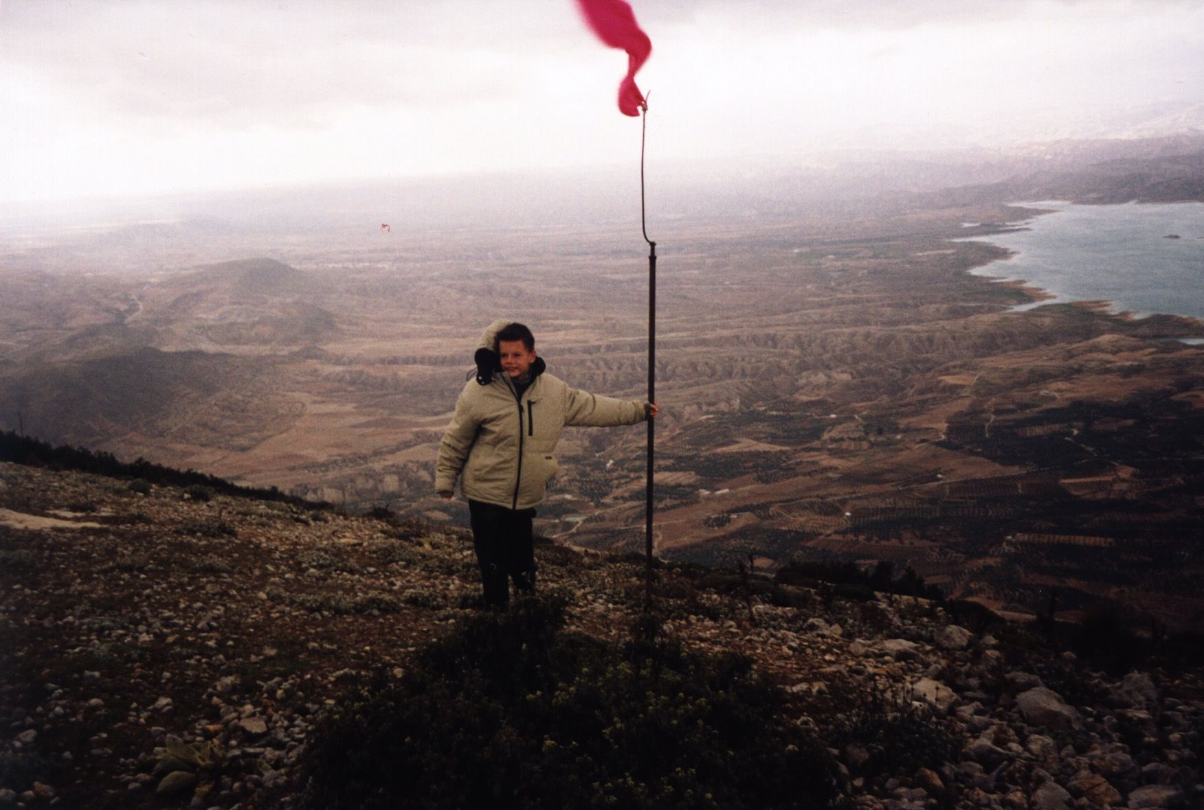 Me standing besides a flag on top of a mountain.