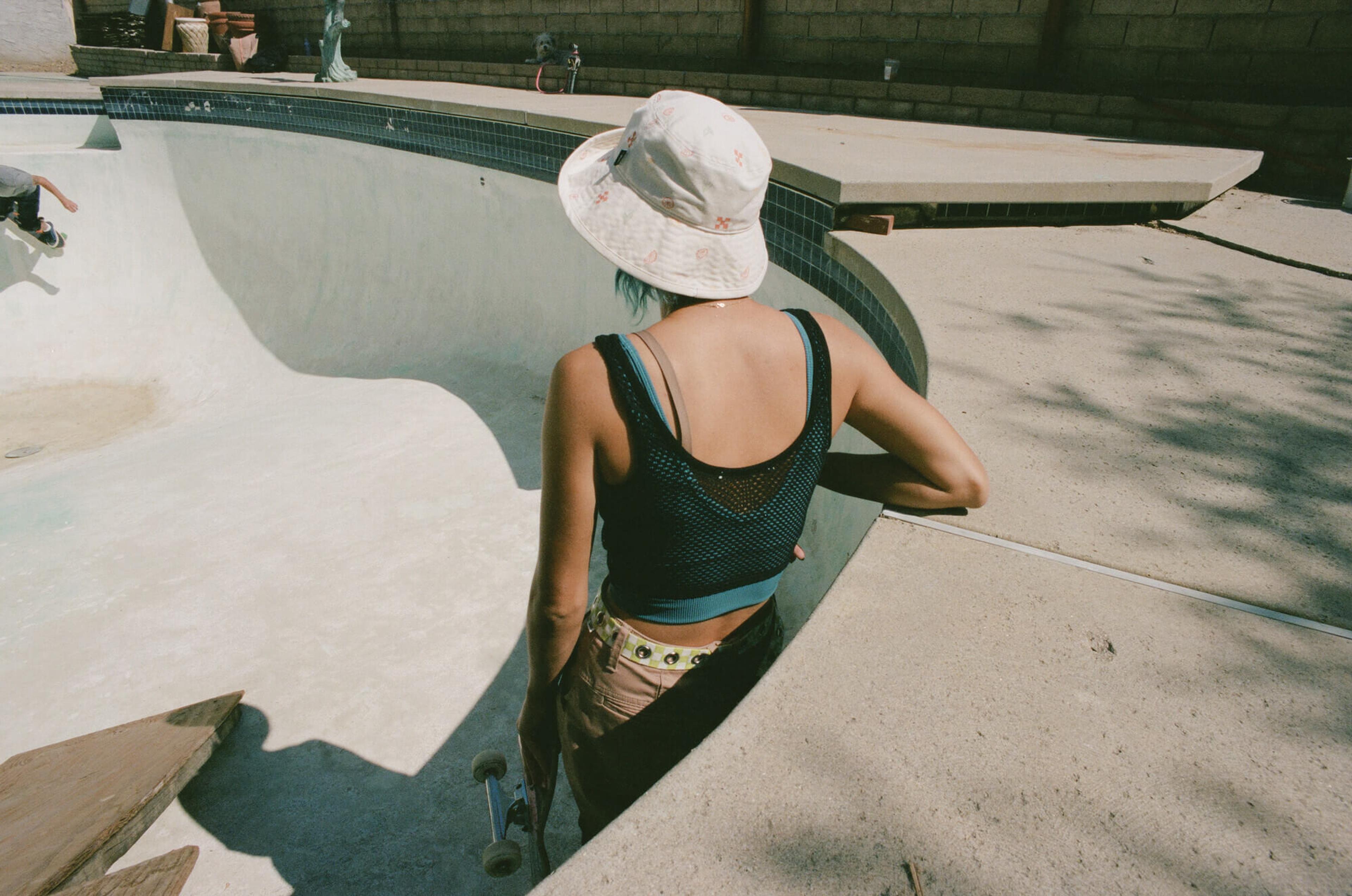 A skater in Vans apparel at the edge of an empty pool