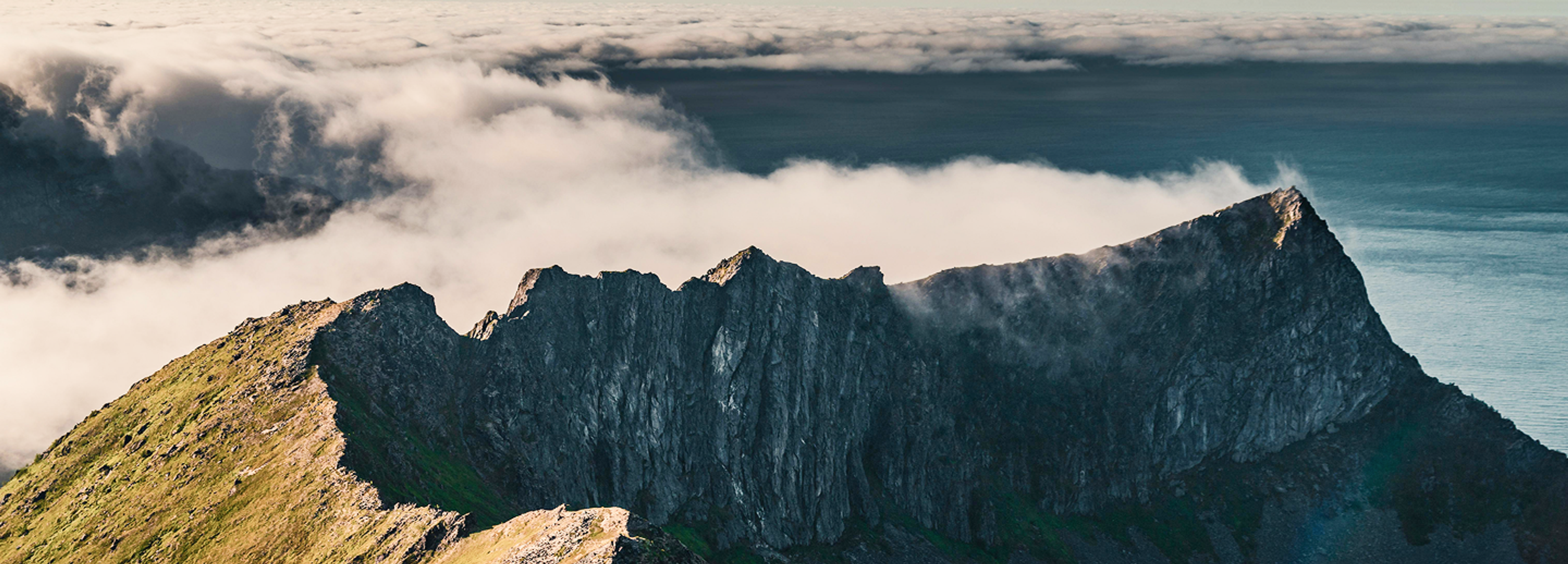 top of a craggy mountain with fog rolling in