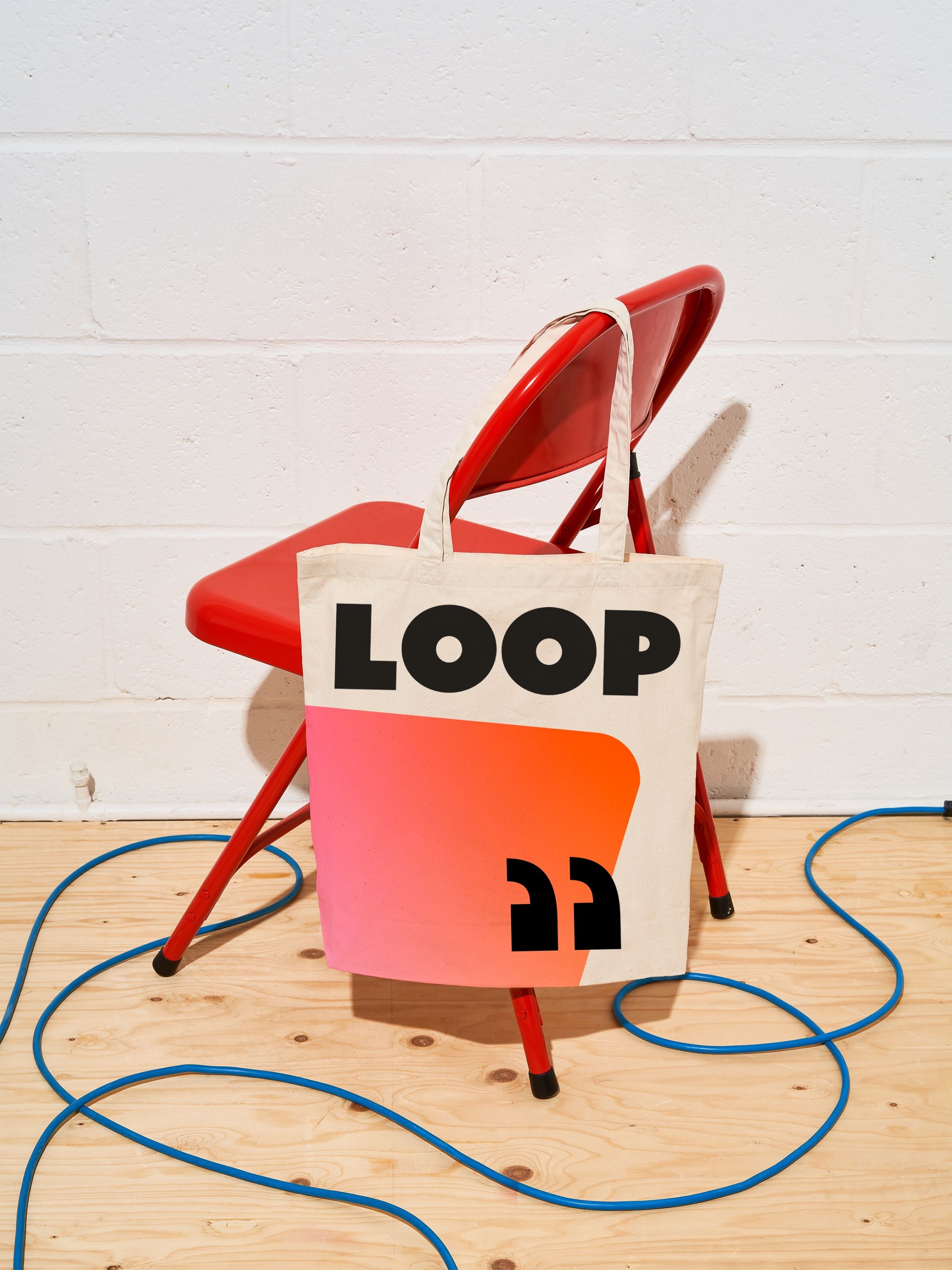 Loop branded tote bag hanging off the back of a red chair