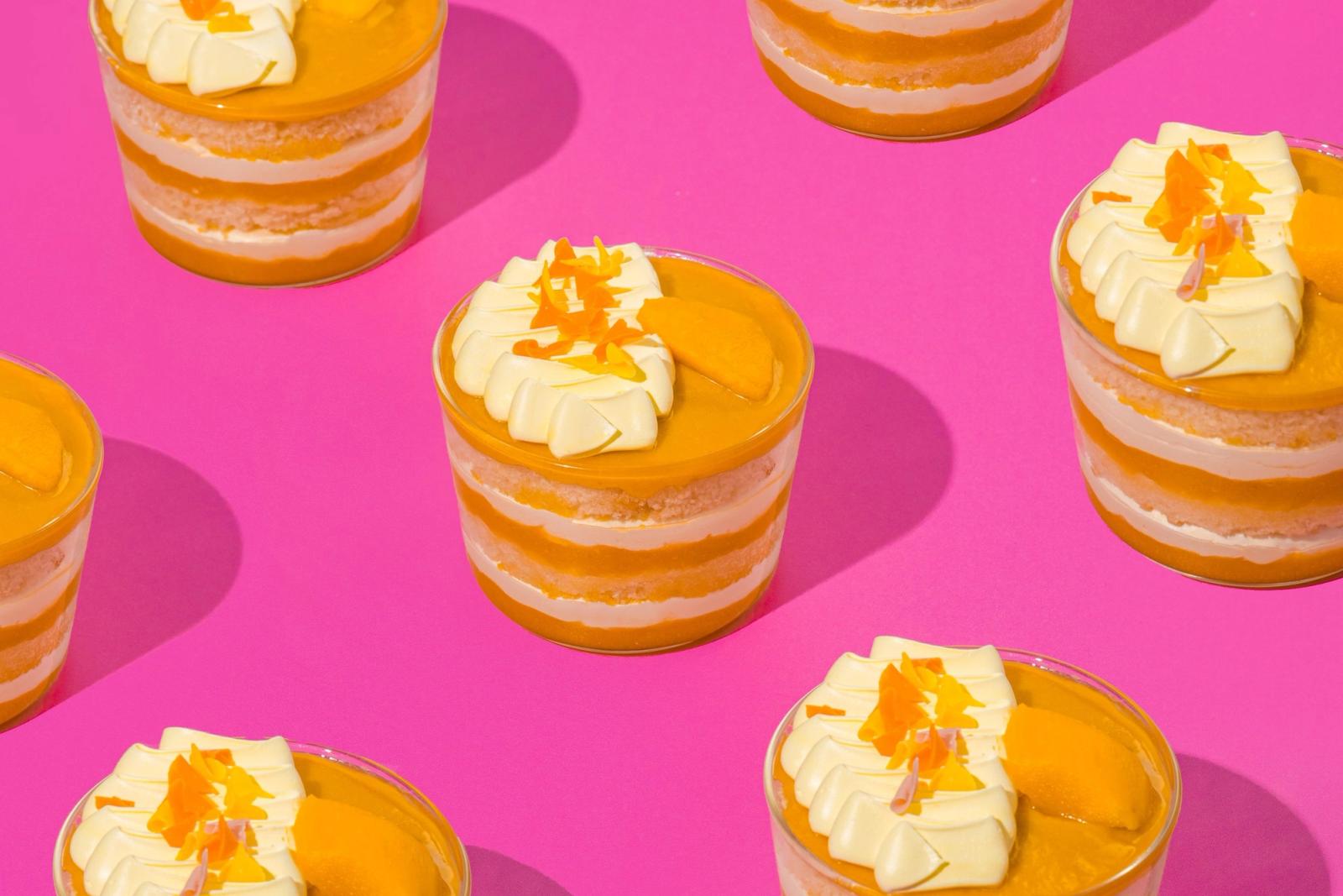 Rows of mango cake cups on a pink background