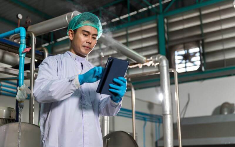 FDA food tracing rules are represented by a food safety worker in a CPG factory tracking goods using technology
