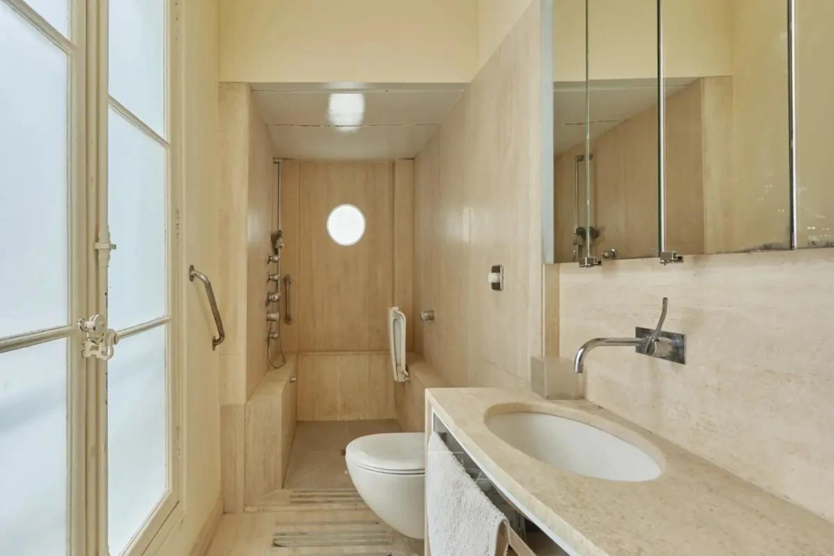 Salle d'eau beige avec douche et vasque