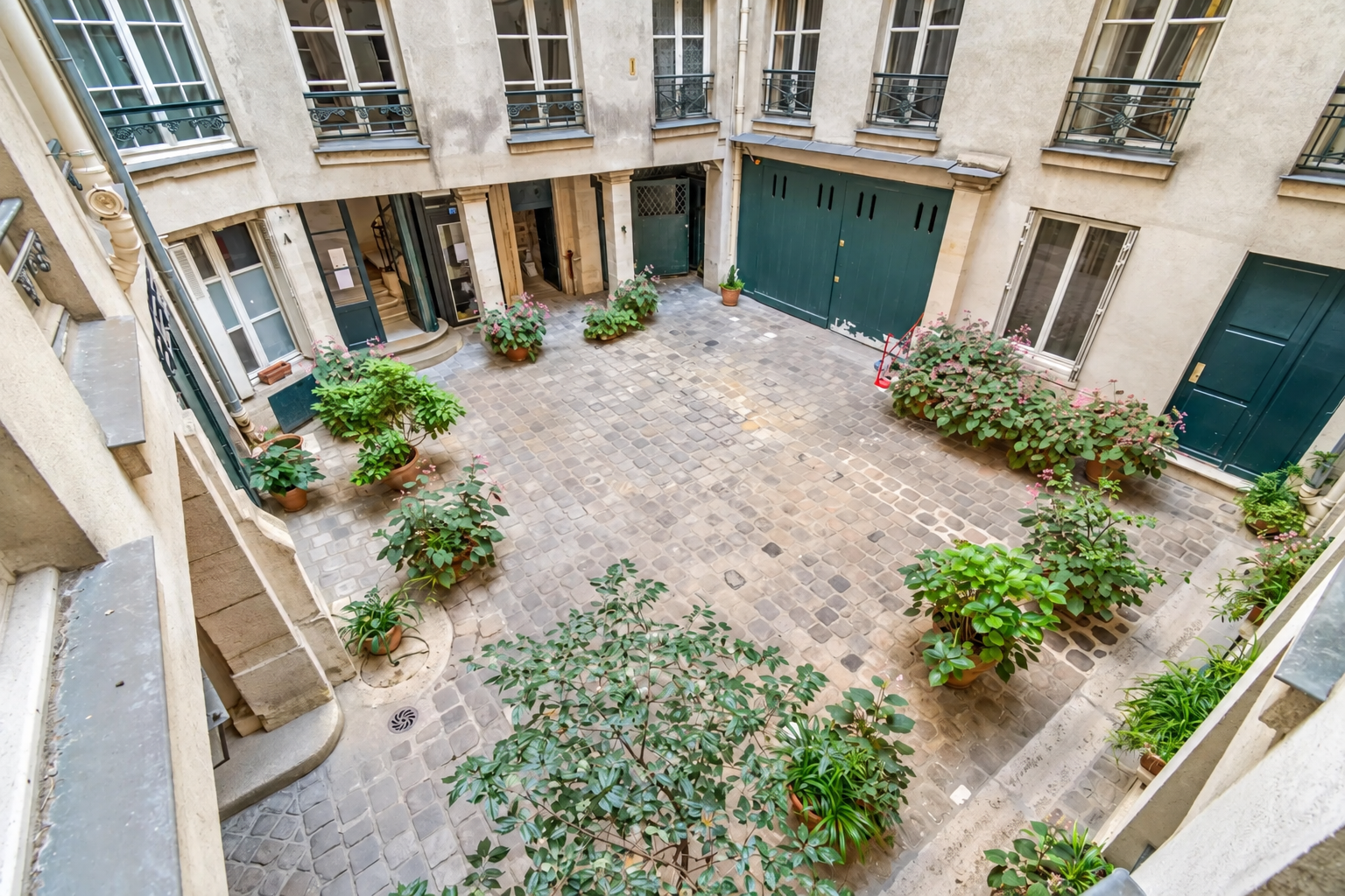 Cour pavée d'un immeuble parisien avec plantes