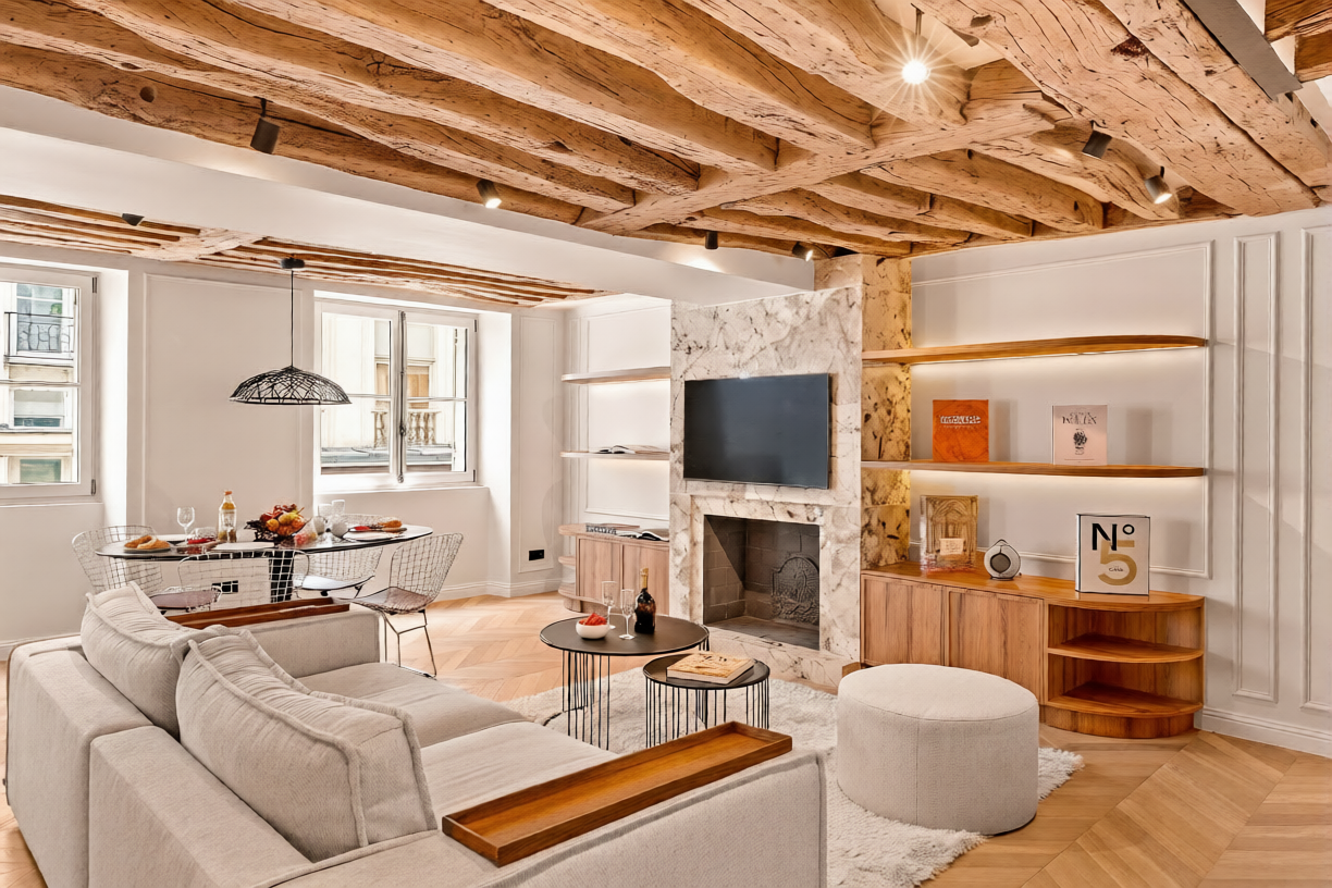 Salon avec poutres de chêne apparentes, cheminée de marbre et canapés en bouclette dans un appartement deux chambres rénové quai Malaquais, Saint-Germain, Paris 6e