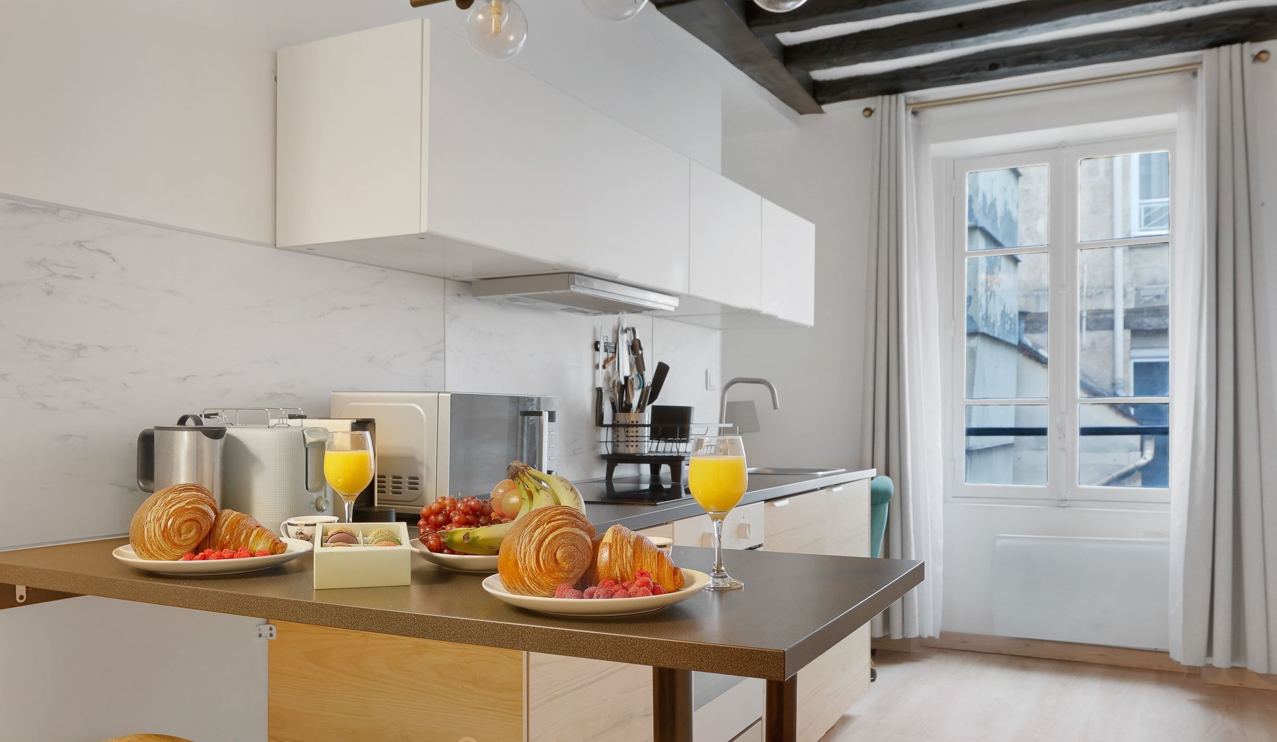 Appartement meublé rue Saint-Séverin Paris 5e, canapé-lit sous des poutres apparentes dans un intérieur du Quartier Latin