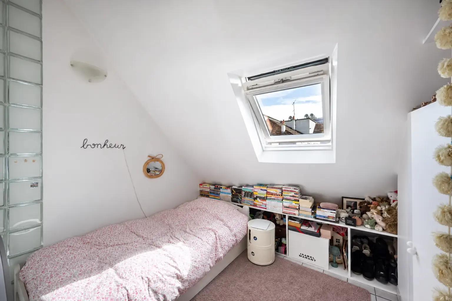 Attic bedroom with roof window and built-in shelves