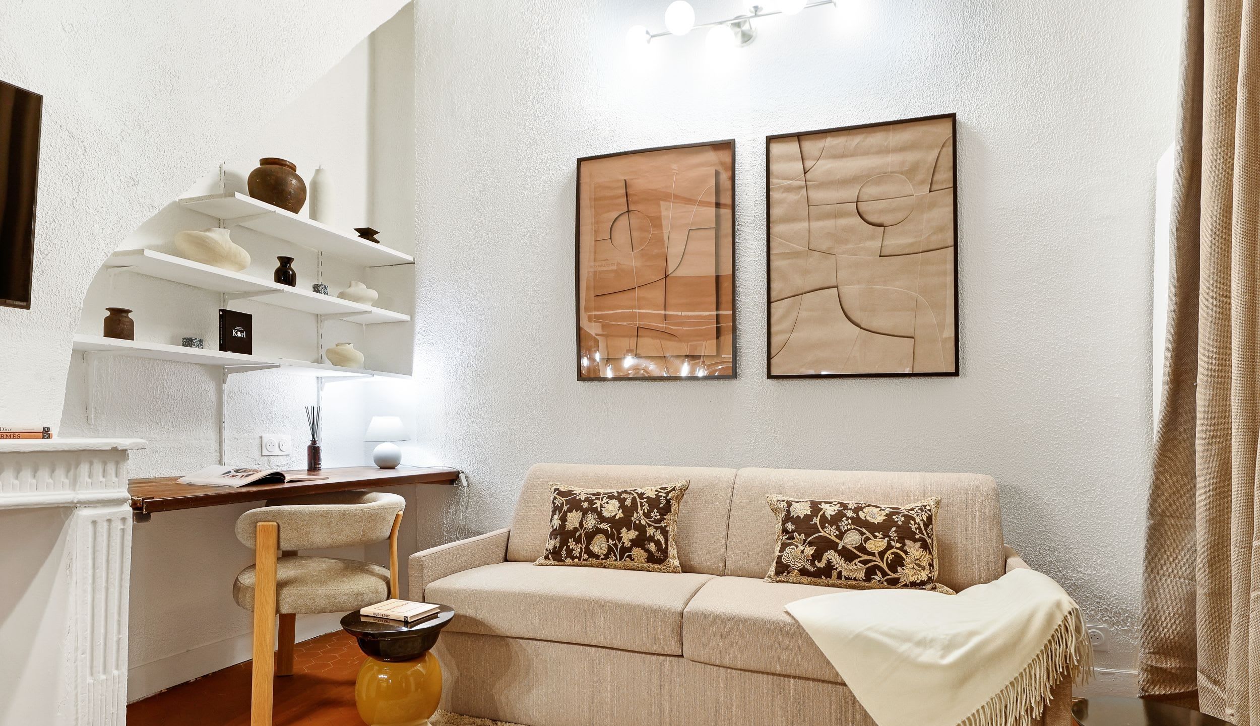 Warm living area with a sofa bed, desk, dining area, and open kitchen.