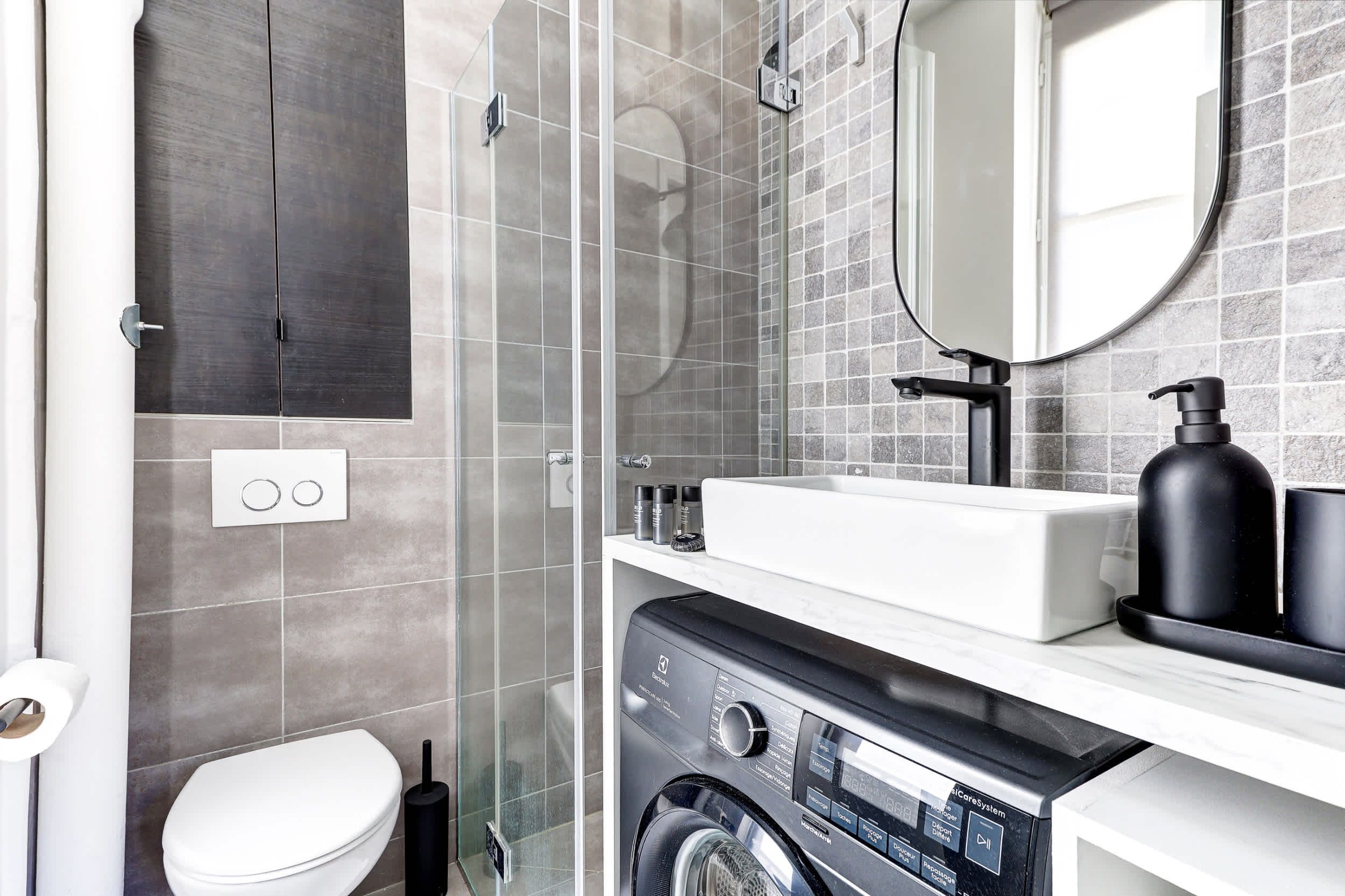 Salle de bain : douche, toilette, lavabo, miroir et lave linge.