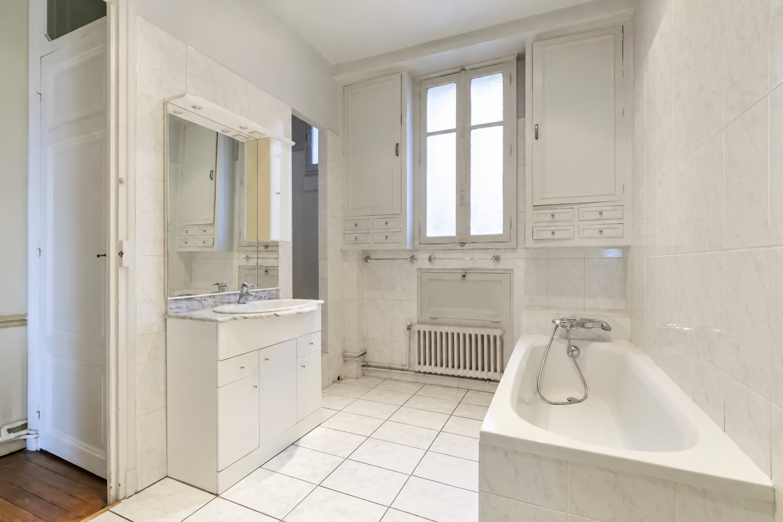Salle de bains blanche avec baignoire et rangements