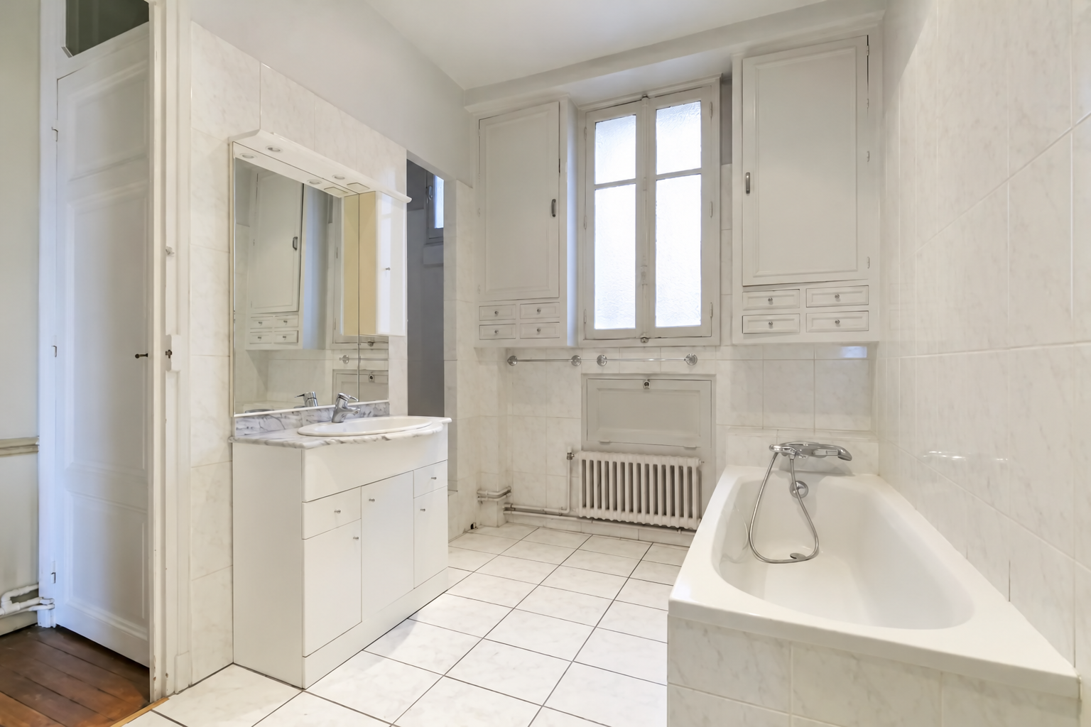 Salle de bains blanche avec baignoire et rangements