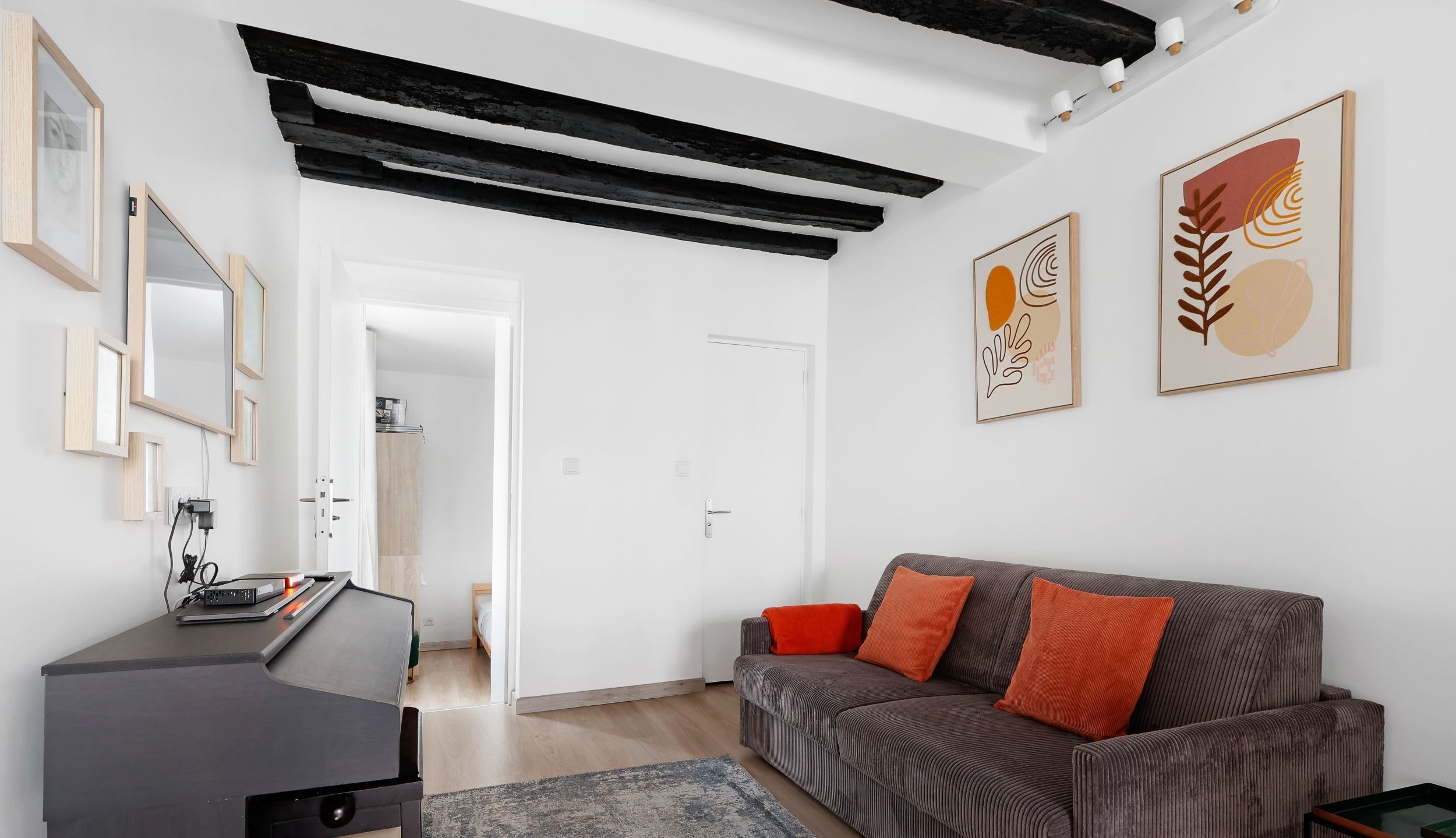 Appartement meublé rue Saint-Séverin Paris 5e, canapé-lit sous des poutres apparentes dans un intérieur du Quartier Latin
