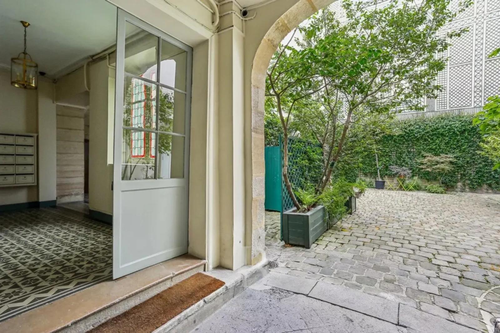 Entrée d'immeuble ancien donnant sur une cour arborée