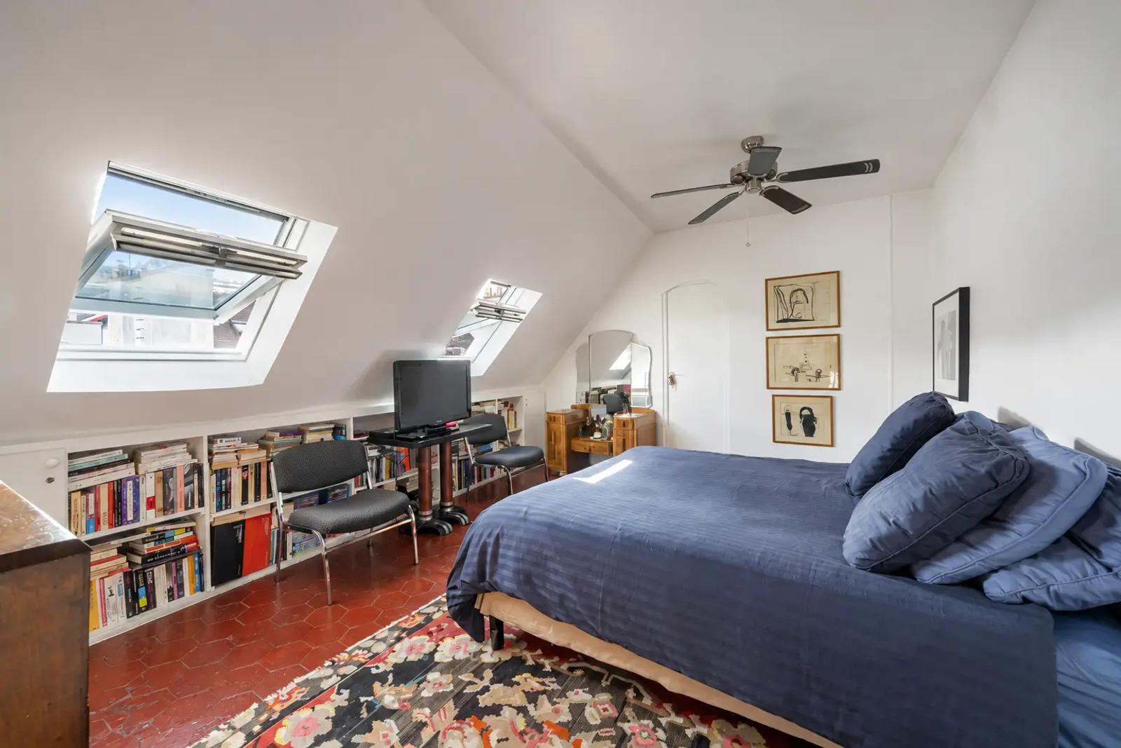 Attic bedroom with blue bedding and low bookshelves
