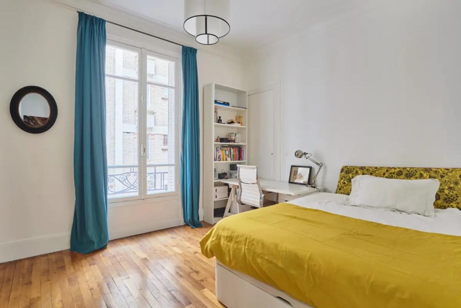 Chambre parisienne avec couvre-lit jaune et fenêtre