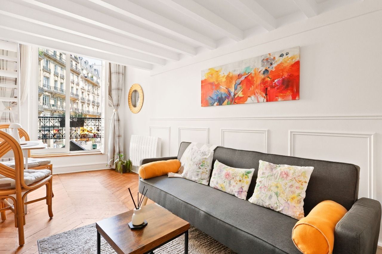 Séjour lumineux avec canapé, cheminée décorative et miroir doré dans un duplex rue Montmartre, Montorgueil, Paris 2e