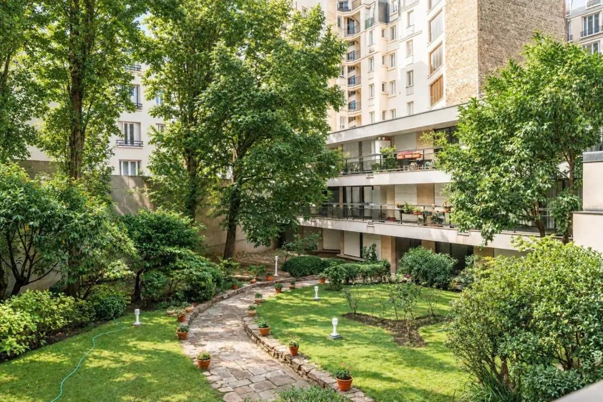 Jardin commun arboré avec allée en pierre