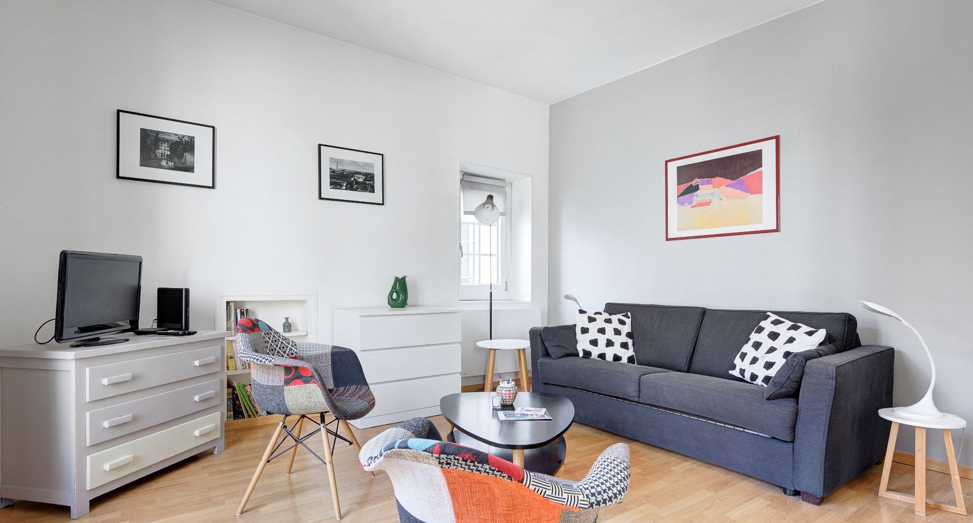 Boho-chic furnished apartment rue Vieille du Temple Marais Paris 4th, bright living room with patchwork armchairs and rooftop views