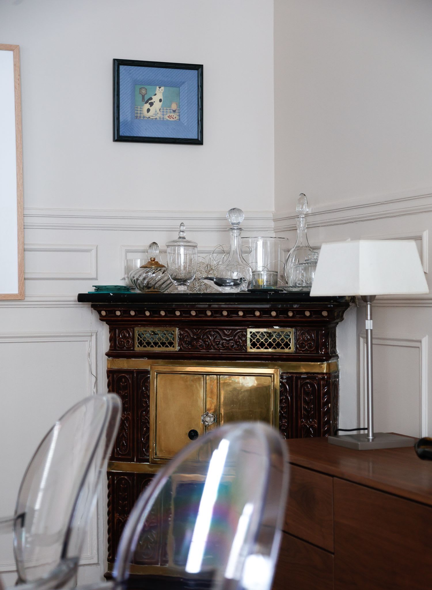 Salle à manger haussmannienne d'un appartement meublé rue Lentonnet Paris 9e, suspension Vertigo au-dessus d'une table ovale et chaises Louis Ghost sous des moulures d'époque