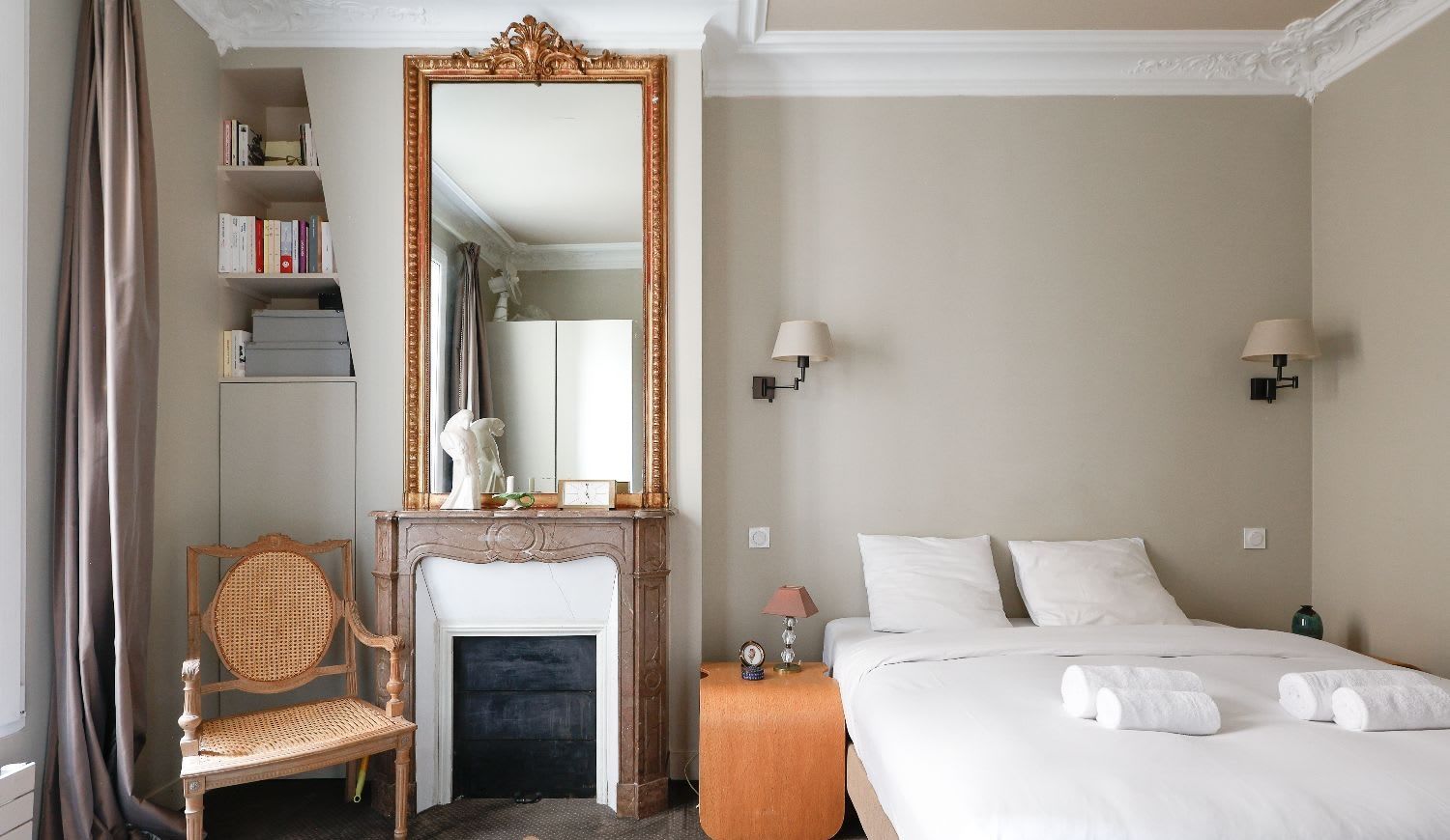 Salle à manger haussmannienne d'un appartement meublé rue Lentonnet Paris 9e, suspension Vertigo au-dessus d'une table ovale et chaises Louis Ghost sous des moulures d'époque